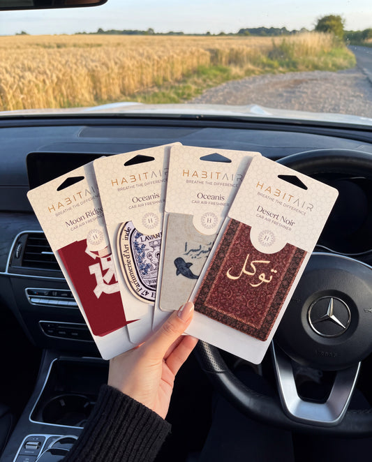 The Journey Bundle: Buy 3 Get 1 Free: hand holding the JDM Spirit, Eau de Lavande, Ease in Every Journey and Tawakkul HabitAir retail packs in a car