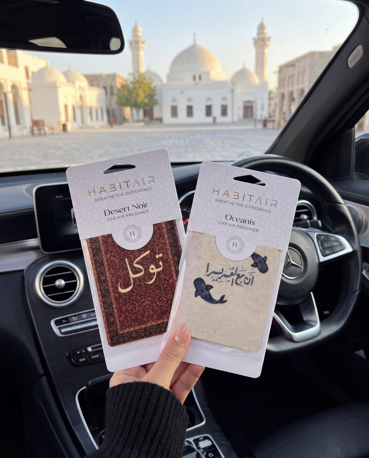 ARABIC DUO BUNDLE: hand holding the Tawakkul and Ease in Every Journey HabitAir retail packs in a car