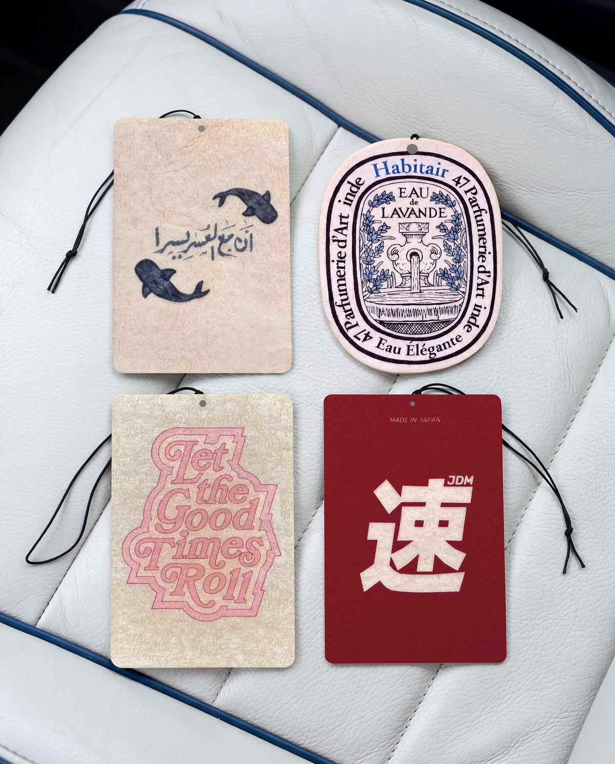 The Signature Bundle: Buy 3 Get 1 Free: Ease in Every Journey, Eau de Lavande, Let the Good Times Roll and JDM Spirit car air freshener cards on a car interior detail