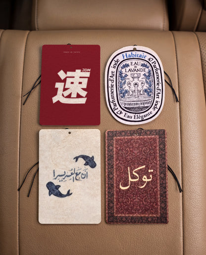 The Journey Bundle: Buy 3 Get 1 Free: JDM Spirit, Eau de Lavande, Ease in Every Journey and Tawakkul car air freshener cards on a car interior detail