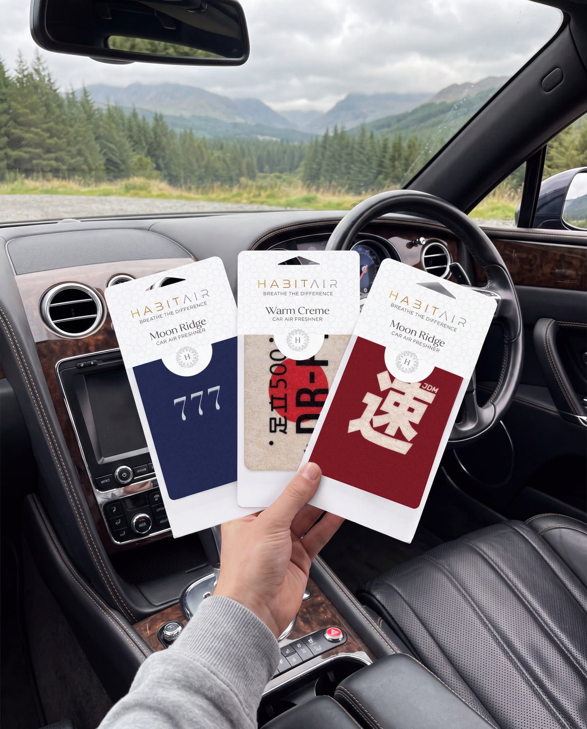 Habitair Trio: JDM LEGENDS — 3 PACK 🏁: hand holding the Lucky 777, DR-FT and JDM Spirit HabitAir retail packs in a car