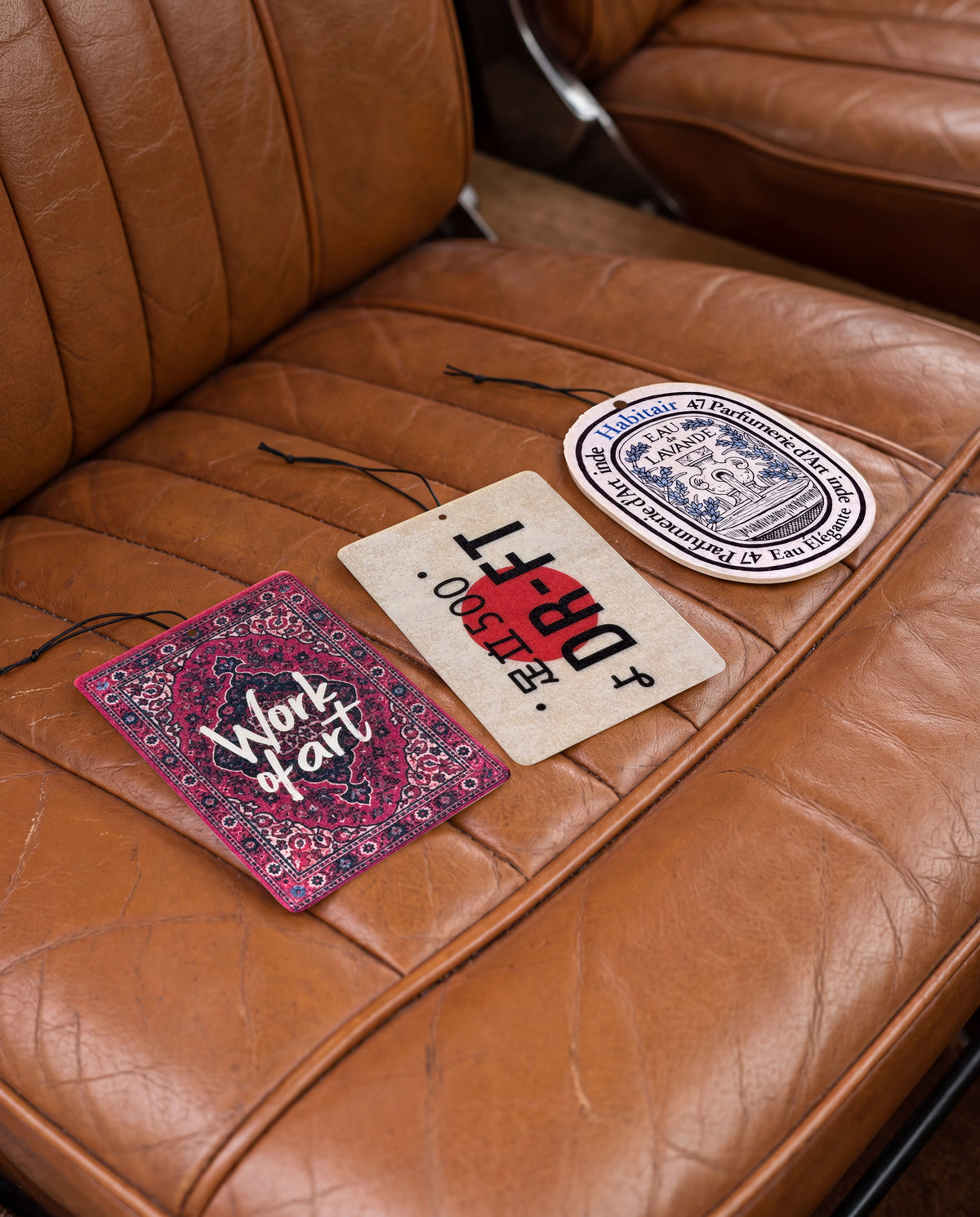 Habitair Trio: The Artisan Collection: Work of Art, DR-FT and Eau de Lavande car air freshener cards on a car interior detail