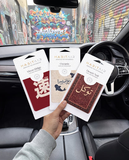 Habitair Trio: The CULTURE Collection: hand holding the JDM Spirit, Ease in Every Journey and Tawakkul HabitAir retail packs in a car