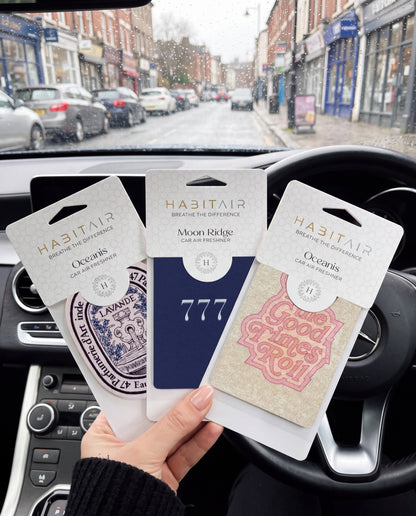 Habitair Trio: The Essentials Collection: hand holding the Eau de Lavande, Lucky 777 and Let the Good Times Roll HabitAir retail packs in a car