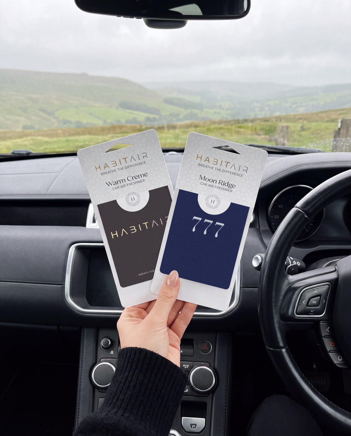The Minimal - DUO: hand holding the Habitair Classic and Lucky 777 HabitAir retail packs in a car